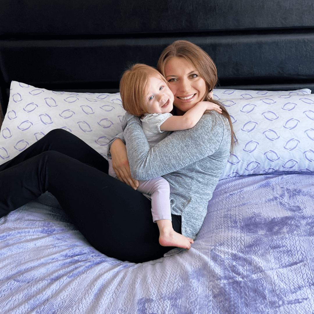 Woman and child sitting on a bed with patterned pillows and bedding